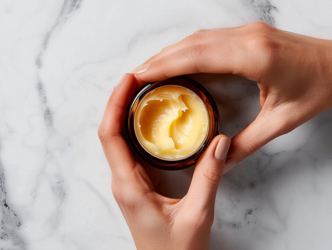 Ever Tallow Balm as a flat lay.  Held by two hands from the right of the frame.