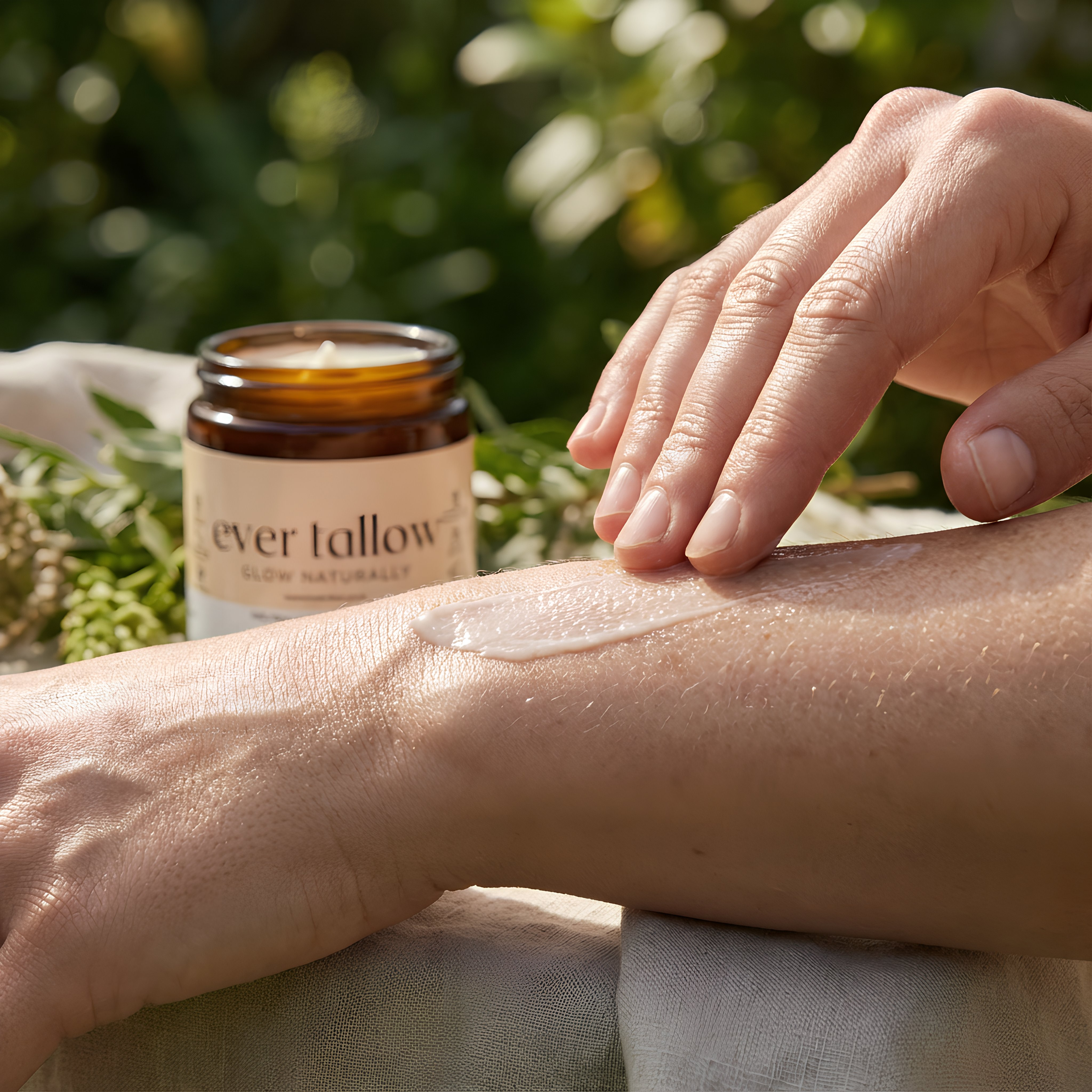 Person applying cream to their arm with a jar of 'ever tallow' bare cream in the background.