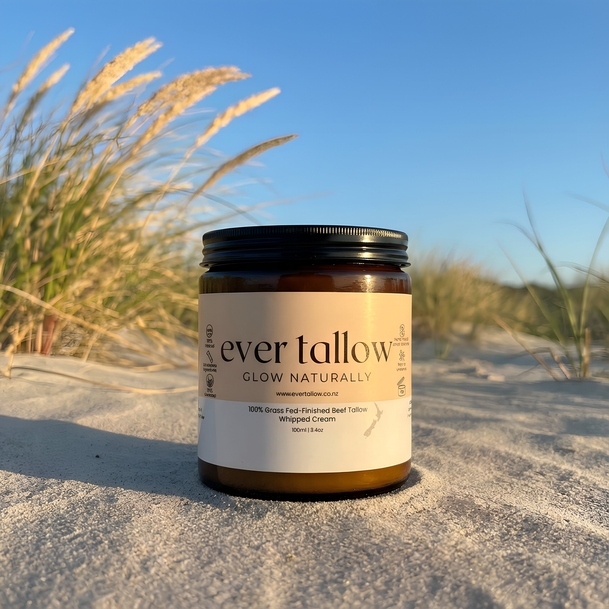 Ever Tallow, Bare Tallow jar on a sandy beach with grasses and clear sky