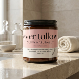 Ever Tallow Beef Tallow with Jojoba Oil, Frankincense, and Rose on a polished stone bathroom counter. Neutral tones. Soft natural light from the side.