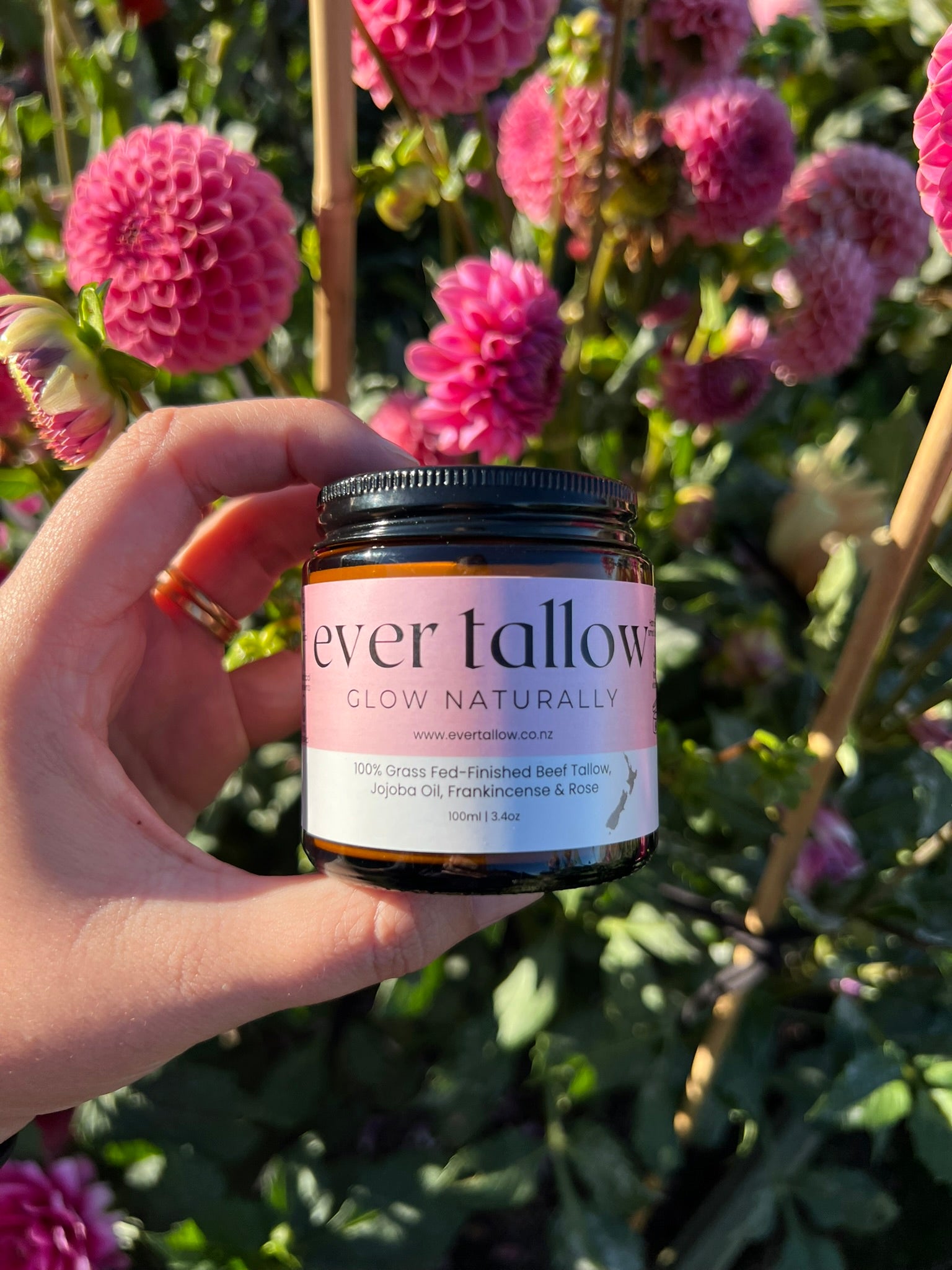 Ever Tallow Beef Tallow with Jojoba Oil, Frankincense, and Rose in front of dahlias in the garden