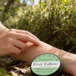 Person applying Ever Tallow balm to their arm with a natural setting in the background