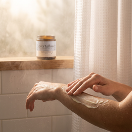 Person applying cream to their arm with a jar of 'ever tallow' in the background, with Lavender and Frankincense Tallow.