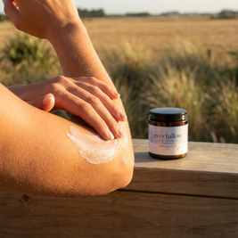 Person applying Lavender and Frankincense tallow to their arm with a jar of Ever Tallow in the background.