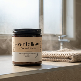 Jar of 'ever tallow' cream on a bathroom counter with a towel and window in the background