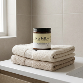 Jar of 'ever tallow' Manuka Honey Tallow on folded towels in a bathroom setting