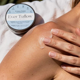 Person applying Ever Tallow balm to their arm with a jar of the product next to them.