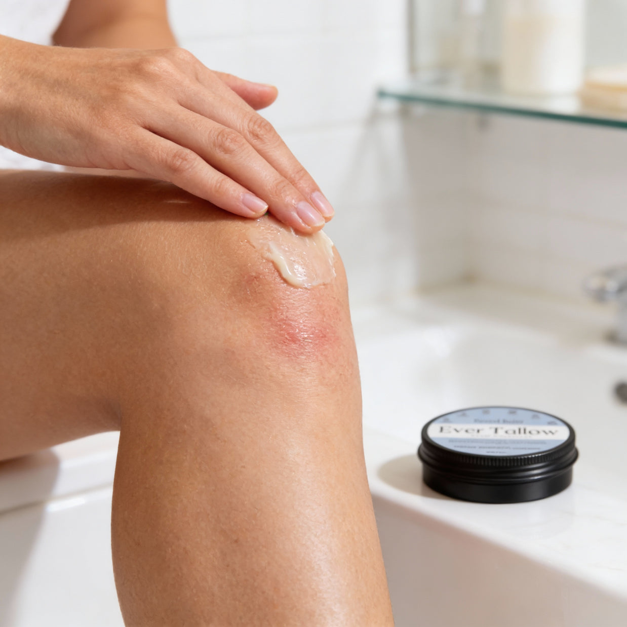 Person applying Winter tallow cream to a knee with a jar of cream in the background