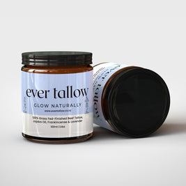 Two jars of tallow cream, frankincense, and lavender. One jar is on its side.